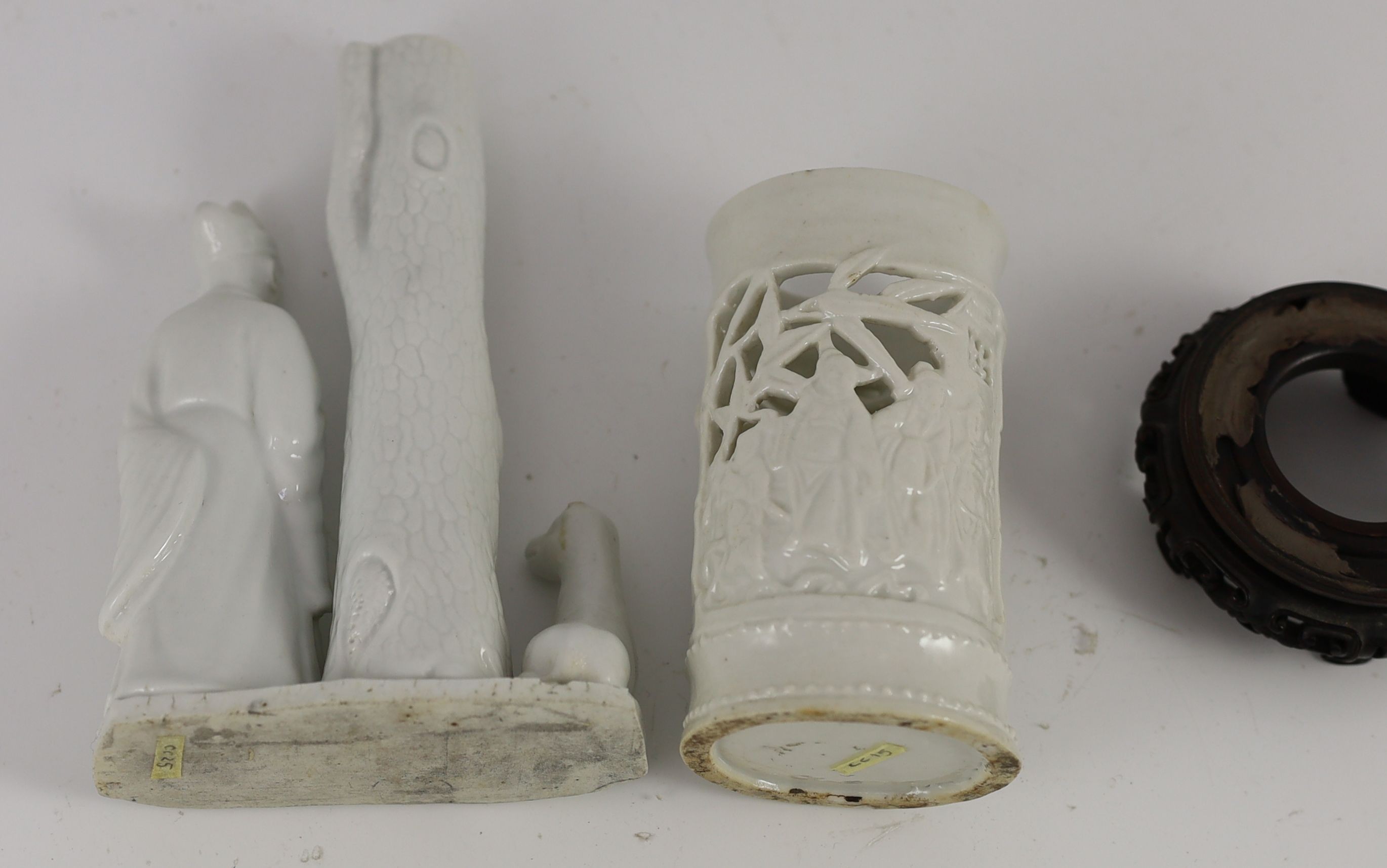 A Chinese blanc-de-chine figural joss stick holder and a similar brushpot, Dehua kilns, 18th/19th century, 16cm high & 11cm plus wood stand